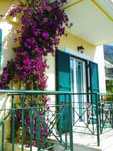 a building with blue shutters and purple flowers at Sundy's Studios in Nydri