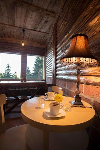 a table with a lamp and coffee cups on it at Guest House Golijski Dar in Dajići