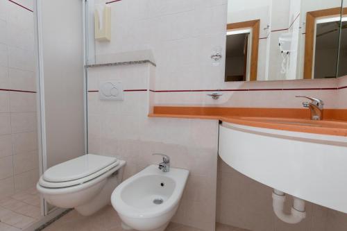 a white bathroom with a toilet and a sink at Hotel Albatros in Rimini