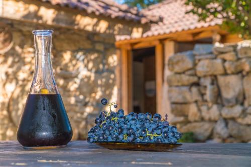 a bottle of wine next to a bunch of blue grapes at Agroturizam Duvančić - Konoba dida Marka in Drniš