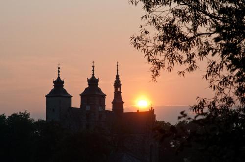 a building with towers with the sunset in the background at Hotel Miodowy Młyn in Opatów
