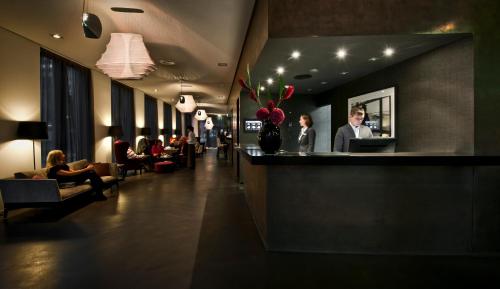 a lobby of a hotel with people sitting in chairs at COSMO Hotel Berlin Mitte in Berlin
