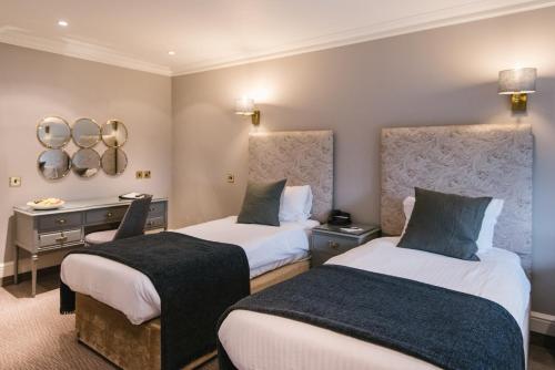 a hotel room with two beds and a mirror at The Spa Hotel in Royal Tunbridge Wells