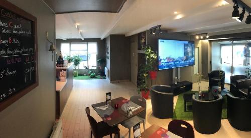 a living room with a tv and a table and chairs at Campanile Colmar - Parc des Expositions in Colmar