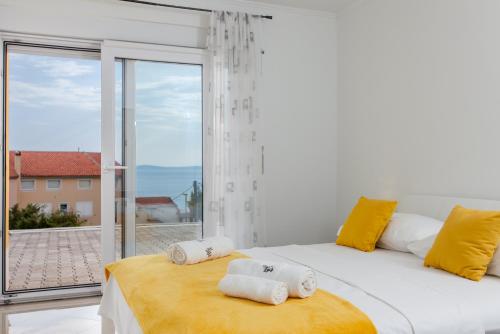 a white bedroom with a large window and a bed at Knezovic Apartments in Podstrana