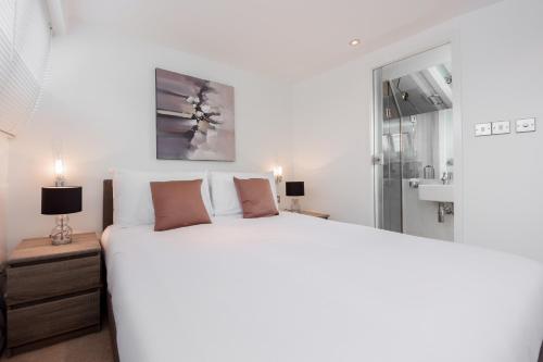 a bedroom with a large white bed and a mirror at Apartment near Harrods in London