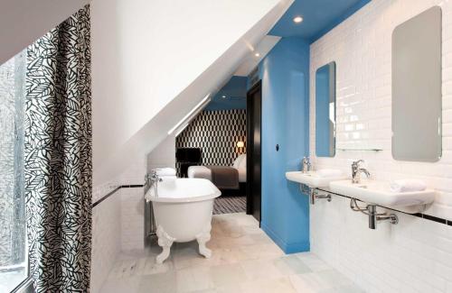 a bathroom with a toilet and two sinks and a bedroom at Hôtel Emile Le Marais in Paris