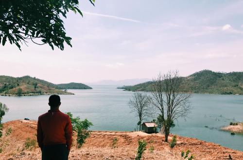 a man standing on a hill looking at a lake at Vietnam Phuot Real Home in Kon Tum