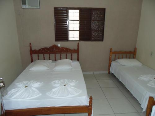 a bedroom with two beds with white sheets and a window at Avenida Hotel in Presidente Prudente