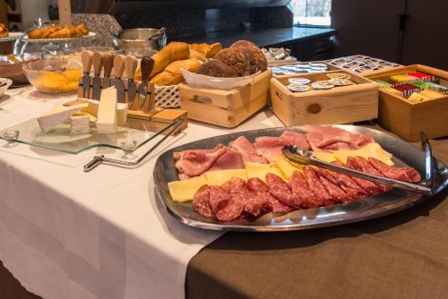 a table with a plate of meats and cheese at Hotel Paradiso in Sarnonico