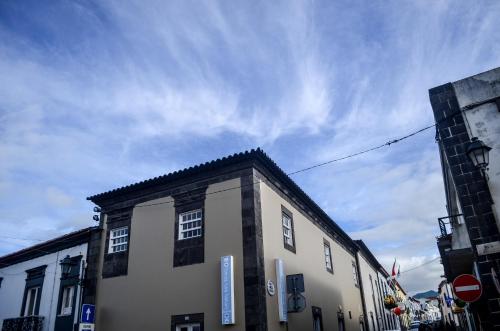 a building on a street with a cloudy sky at A Casa del Rei in Ribeira Grande