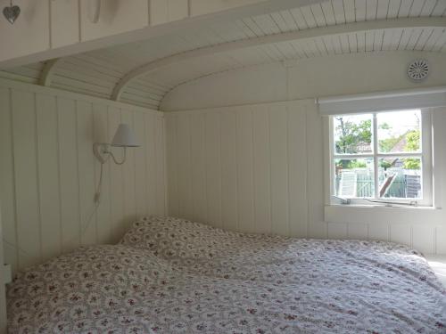 Schlafzimmer mit einem Bett und einem Fenster in der Unterkunft pipowagen Blagour gelegen aan waterbron in Lachapelle-Auzac