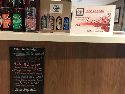 a counter with a shelf with bottles of alcohol at Campanile Colmar - Parc des Expositions in Colmar
