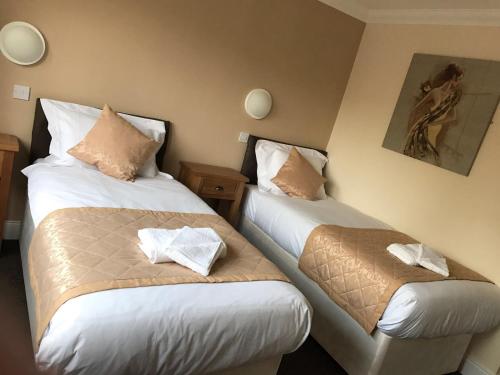 two beds in a hotel room with towels at The Waverley Inn in Dingwall