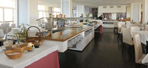 a large kitchen with a counter and tables and chairs at Hotel Salobreña Suites in Salobreña