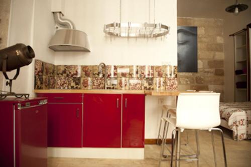 アヴィニョンにあるCité des Papesのキッチン(赤いキャビネット、白い椅子2脚付)