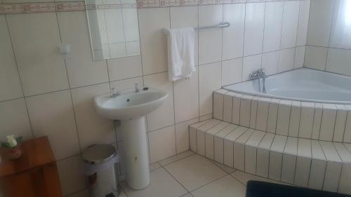 a white bathroom with a sink and a tub at Thula Du Estate - family houses in Mbabane