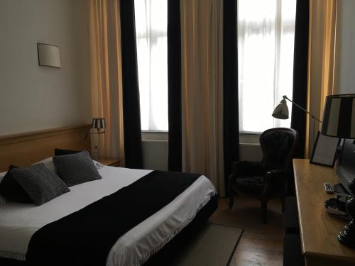 a bedroom with a bed and a desk and two windows at Chambres D'Hotes Rekko in Maastricht