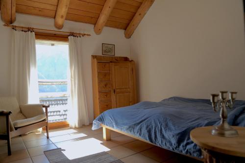 ein Schlafzimmer mit einem Bett, einem Stuhl und einem Fenster in der Unterkunft Casa Dosc in Verdabbio