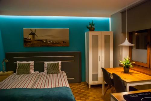 um quarto com uma parede azul com uma cama e uma mesa em Apartamenty Akacjowa przy Parku Szwedzkim em Szczawno-Zdrój