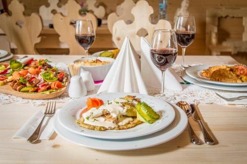 a table with a plate of food and glasses of wine at "Plai cu Peri" in Săpînţa