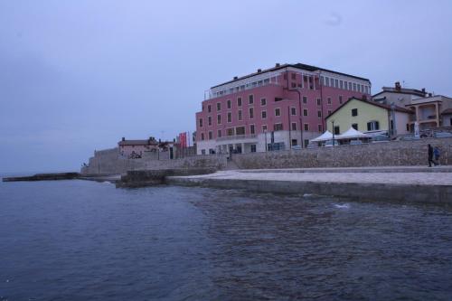 a large red building next to a body of water at Apartments Tomato in Novigrad Istria