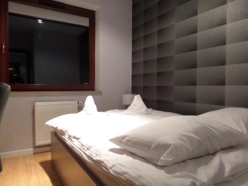 a bedroom with a white bed with a large headboard at Pohulanka Luxury in Gdańsk