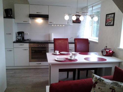 a kitchen with a table and red chairs in a room at Oldenstadter Wassermuhle in Uelzen