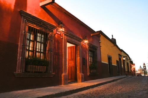 
a red brick building with a clock on the side of it at Clandestino Hotel - Adults Only in San Miguel de Allende
