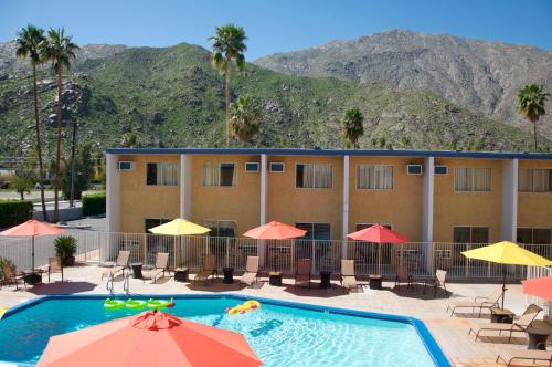 Delos Reyes Palm Springs في بالم سبرينغز: فندق فيه مسبح وجبال في الخلف