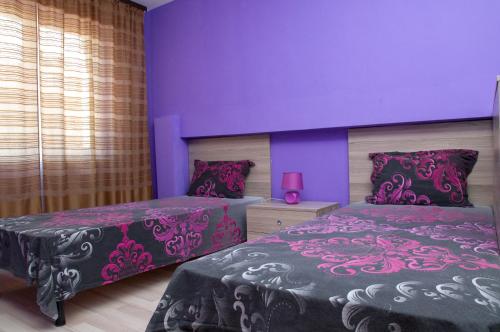 two beds in a room with purple walls at Apartment Medical University in Pleven