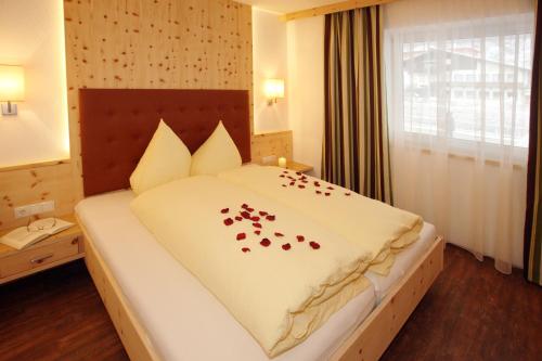 a bedroom with a bed with red rose petals on it at Appartements Alpenkristall in Zell am Ziller