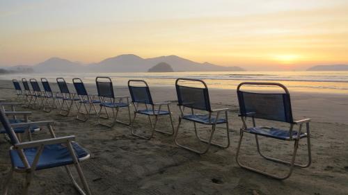 a row of chairs on the beach at sunset at Pousada Casa na Praia in Ubatuba