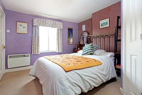 a bedroom with a large bed with purple walls at Grayling House in Stoford