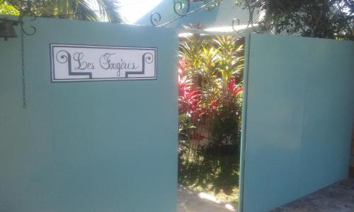 a gate to a garden with a sign that reads las springs at Les Fougères in Baie-Mahault