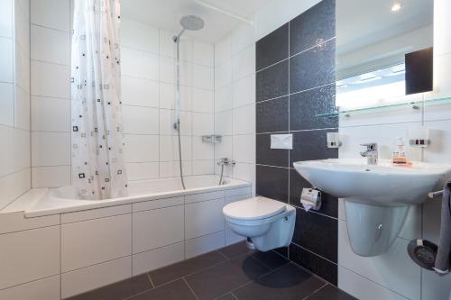 ein Badezimmer mit einem Waschbecken, einem WC und einer Badewanne in der Unterkunft Superior Apartment Sarnen in Sarnen