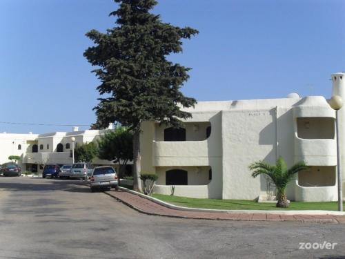 un edificio blanco con un árbol al lado de una calle en Apartamento Das Chamines, en Carvoeiro