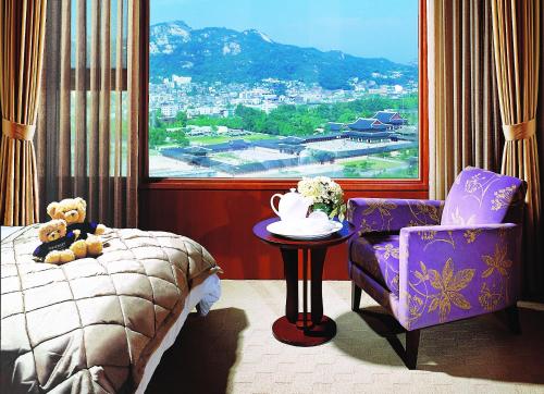 a bedroom with a bed and a chair and a window at Somerset Palace Seoul in Seoul