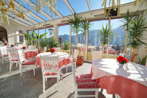 a dining room with tables and chairs in a conservatory at Hotel Glocknerhof in Berg im Drautal
