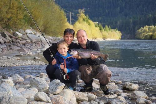 two men and a child holding a fish on a river at Hotel Glocknerhof in Berg im Drautal