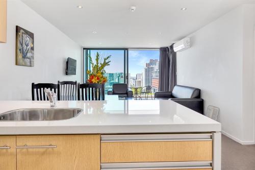 a kitchen with a sink and a living room at Quest on Hobson Serviced Apartments in Auckland