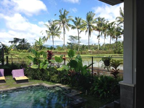 una piscina resort con palmeras en el fondo en Villa Kemuning, en Tegalalang