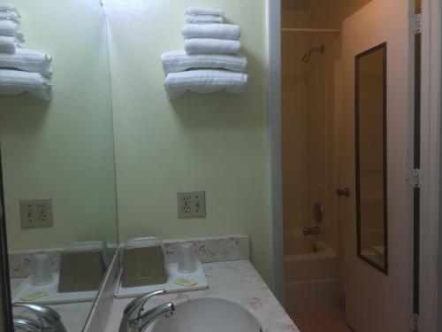 y baño con lavabo, espejo y toallas. en Maple Leaf Inn & Suites, en Kissimmee