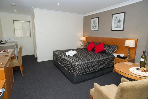 Habitación de hotel con cama con almohadas rojas en The Grapevine Motel en Denman