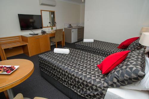 Habitación de hotel con 2 camas, escritorio y TV. en The Grapevine Motel, en Denman