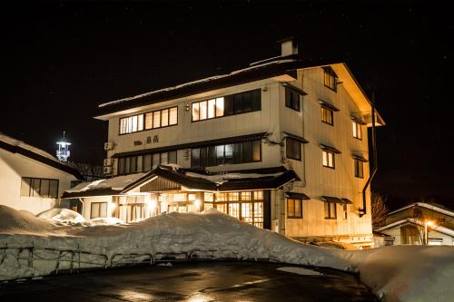 a building at night with snow in front of it at Alpine Villa Nozawa in Nozawa Onsen