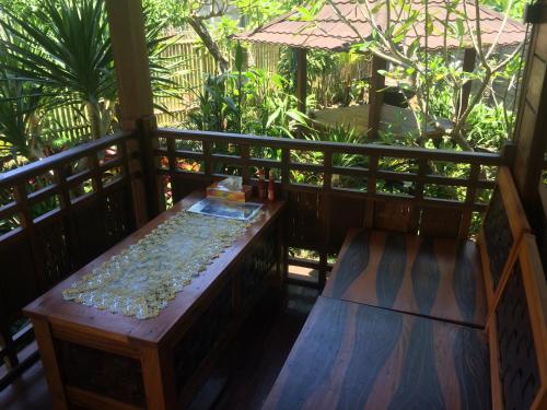 a wooden porch with a bench and an umbrella at Khoo Villa in Senggigi 