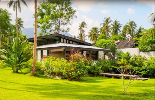 
a house with a large lawn and trees at SomeWhere Else Boutique Resort in Mambajao
