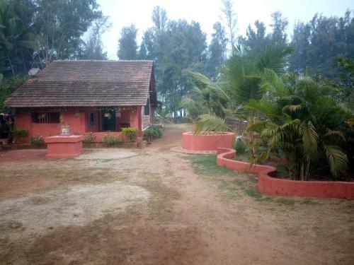 a small red house with a palm tree in front of it at Samarth Atc-Beach Home Stay in Ratnagiri