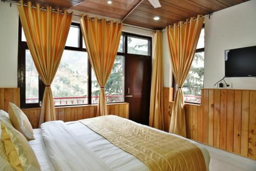 a bedroom with a bed and a tv and windows at Hotel Akash - Luxury Hotel In McLeodganj in McLeod Ganj
